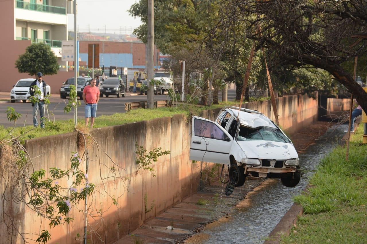 Carro bate em guard rail, capota e cai em córrego na Capital